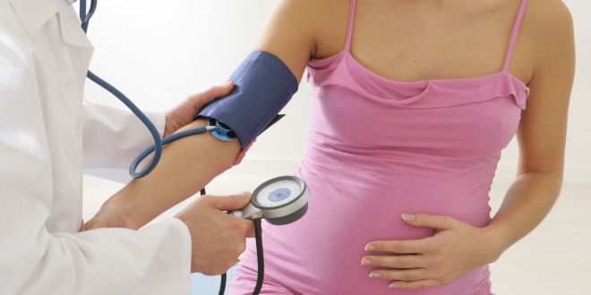 Arzt misst den Blutdruck einer schwangeren Frau