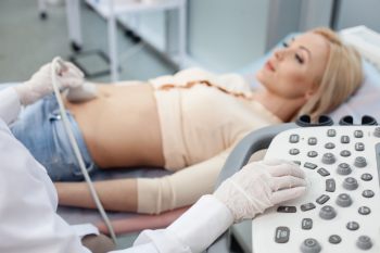 Diagnose von Morbus Crohn Arzt führt Abdomen-Sonographie einer liegenden Patientin durch