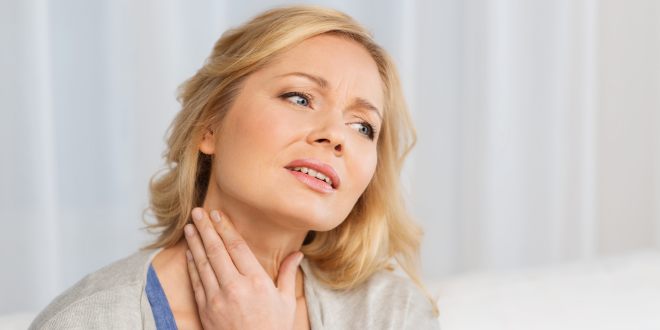 Frau greift sich bei schmerzenden Lymphknoten an den Hals 