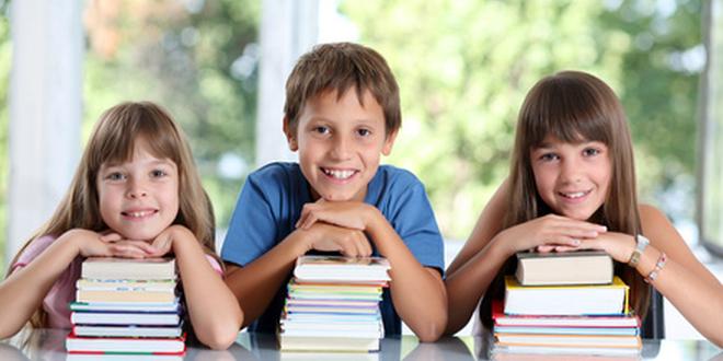 Drei Kinder mit Stapel verschiedener Bücher während der Schulpause