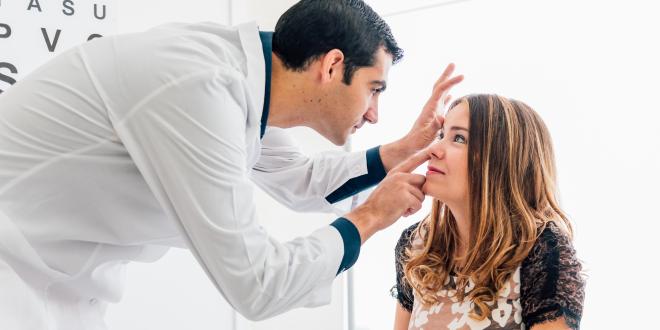 Mann untersucht Frau auf Augenerkrankungen