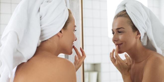Eine Frau cremt sich ihre trockenen Lippen ein