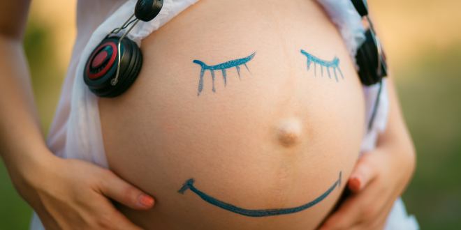 Bauch einer schwangeren Frau mit aufgemaltem Smiley