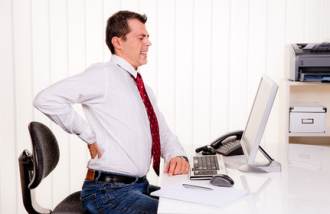 Mann mit Rückenschmerzen am Schreibtisch